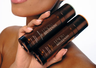 Hands holding two skincare bottles against skin background. Text: "LENOX AND SIXTEENTH. THE PRESERVATIONIST VITAMIN C CREAM SERUM 30 ML / 1.1 FL OZ. THE LASER SERUM TRIPLE ACID CONCENTRATE 30 ML / 1.1 FL OZ."